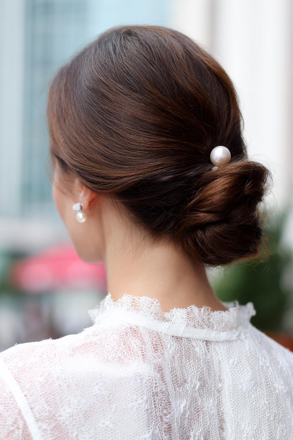 14. Kapsels zonder föhnen: de lage, zijwaartse chignon met gedraaide nekpartij en parelspeld