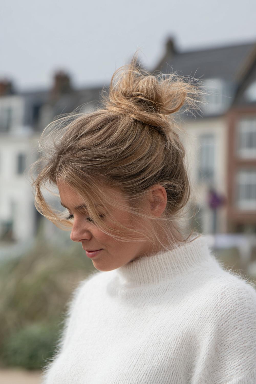 1. Messy bun met midden-scheiding en zachte face-framing lokken