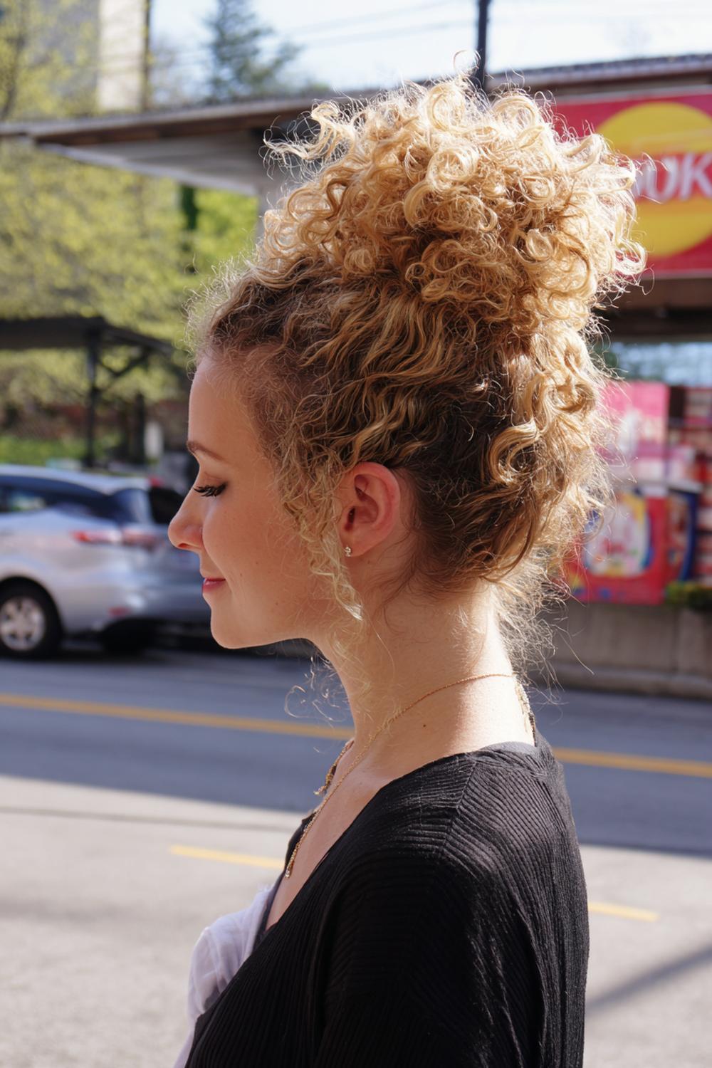 15. Messy bun met natuurlijke krullen en “pineapple” volume