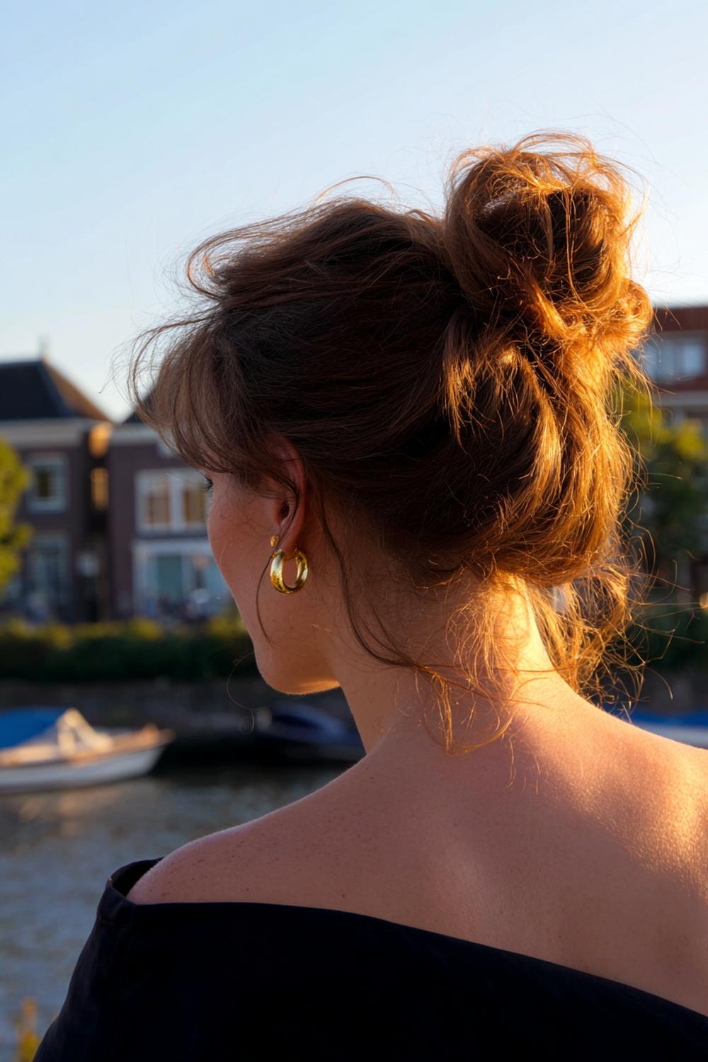 31. Messy bun met warm koper haar en golden-hour glans