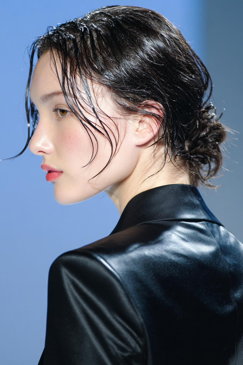 10. Nieuwe Haarstijlen 2026: ‘Wet look’ lage knot met glanzende zijkanten en losse lok